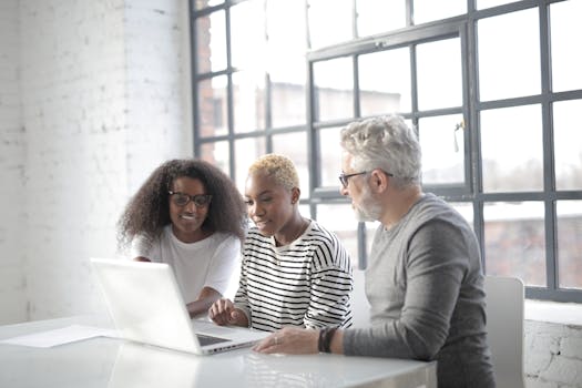Concentrated freelancer in informal outfit discussing project while working remotely and surfing laptop in light coffee shop at daytime