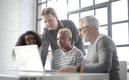 Free Focused coworkers of different ages in casual wear having online conference on laptop while gathering together in modern workspace Stock Photo