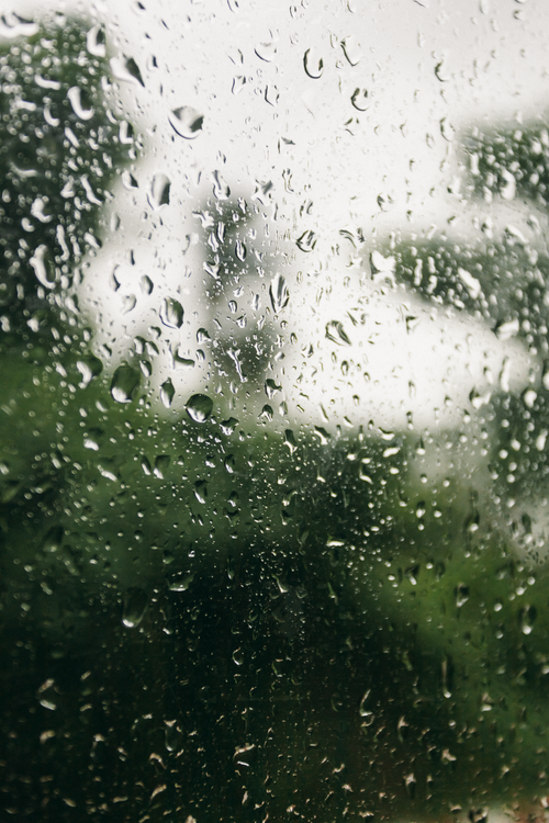 Free Close-up of raindrops on glass with a blurred green outdoor backdrop in Vietnam. Stock Photo