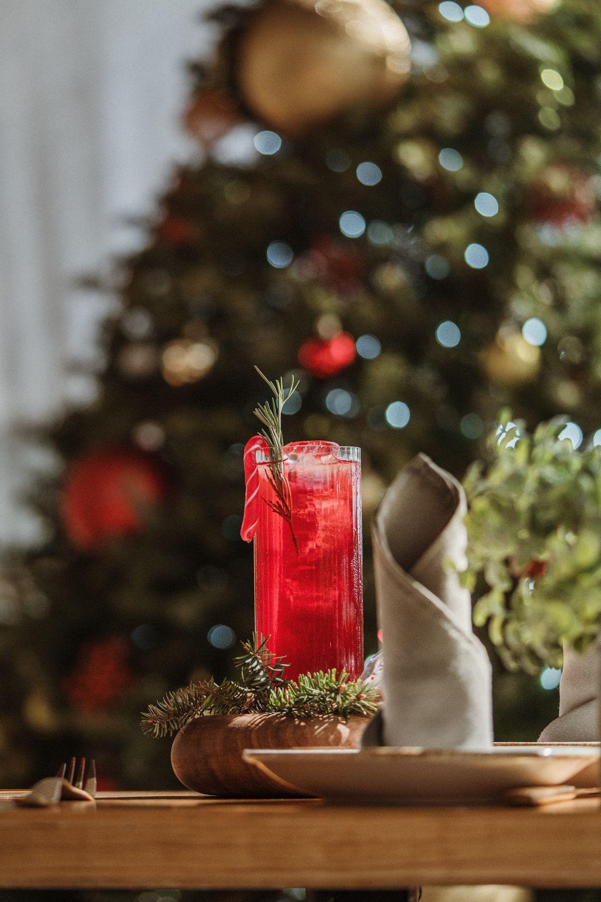 Red cranberry cocktail in front of a decorated Christmas tree