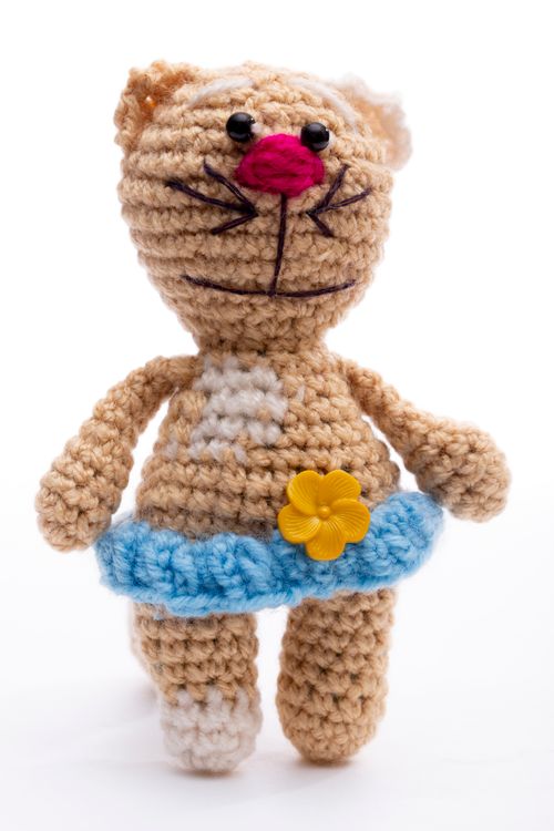 Free Cute crocheted cat doll wearing a blue skirt with a yellow flower, perfect for kids. Stock Photo