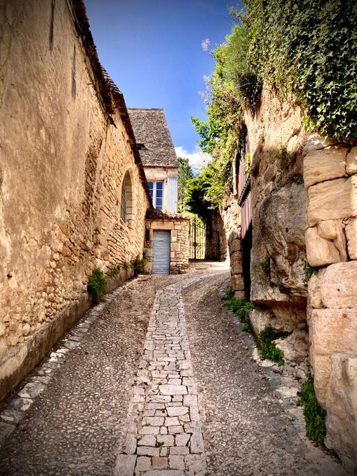 Free Explore a quaint cobblestone street in a historic French village basking in summer sunshine. Stock Photo