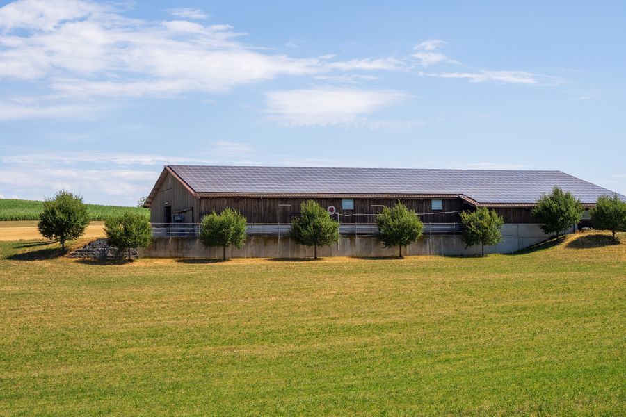 A solar-powered barn in a sunny rural landscape with green fields.