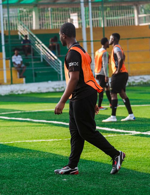 Free Young athletes practice soccer on a vibrant green field, wearing orange training vests. Stock Photo