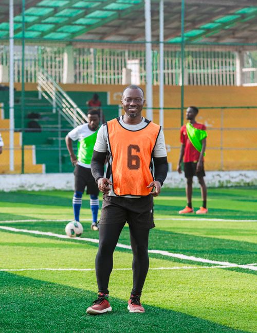Free Smiling soccer player wearing orange bib during practice on outdoor field. Stock Photo