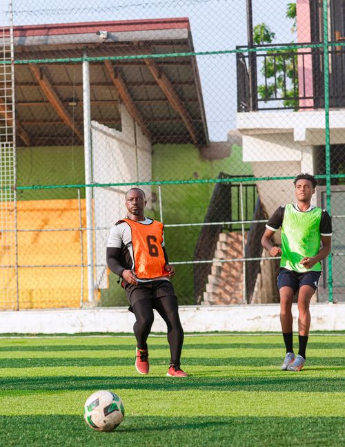Free Two men wearing bibs playing soccer on an outdoor field in the daytime. Stock Photo