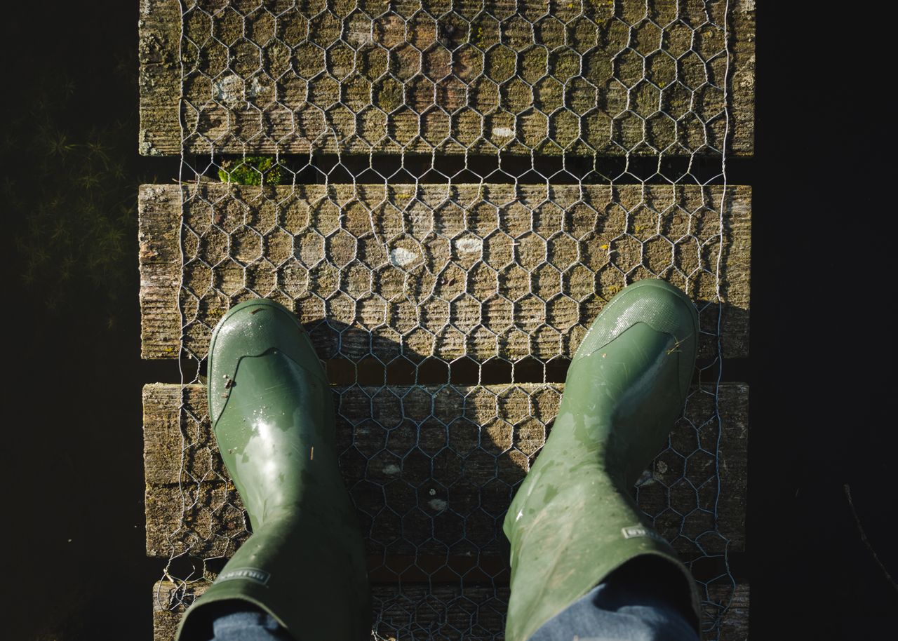 green rubber boots on a weathered wooden bridge