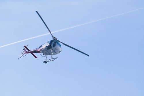 Free A helicopter in flight against a bright blue sky with a contrail visible. Stock Photo