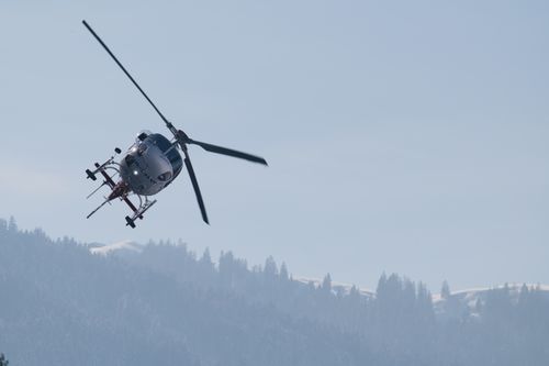Free A helicopter flying over the scenic snowy peaks of the Swiss Alps on a clear winter day. Stock Photo