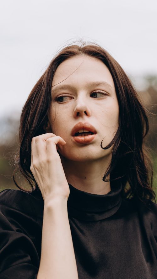 Free Close-up portrait of a young woman with thoughtful expression, outdoors. Stock Photo