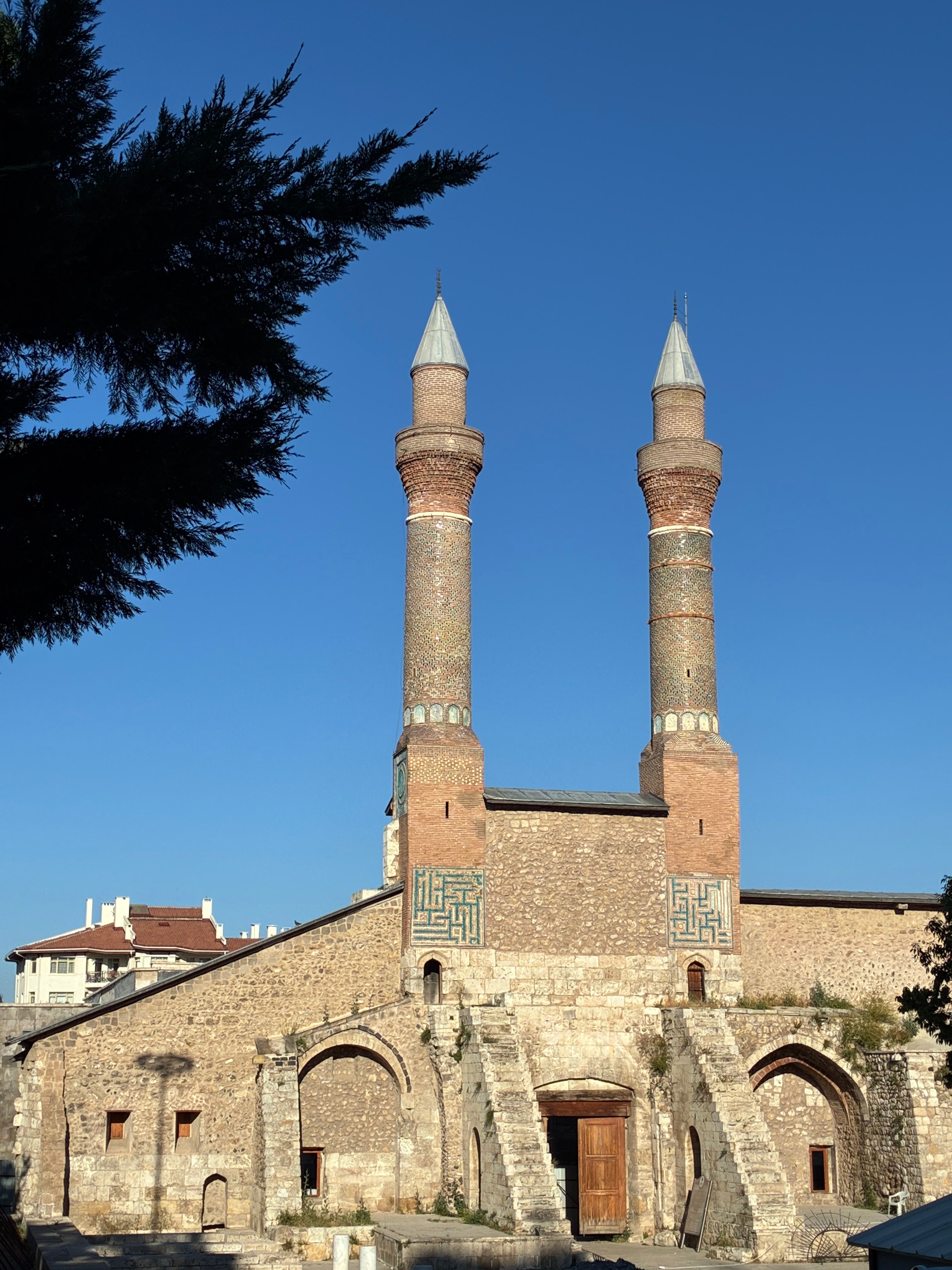 Gök Medrese in Sivas, Turkey with its twin minarets under a clear blue sky.