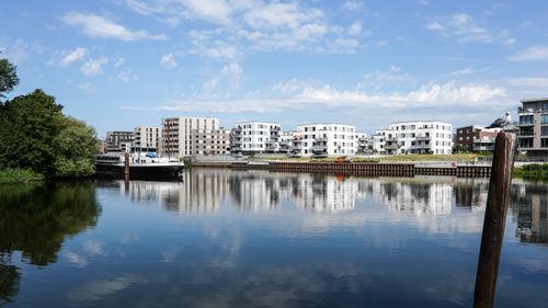 Free Scenic view of modern apartments reflecting on a serene river in Geesthacht. Stock Photo
