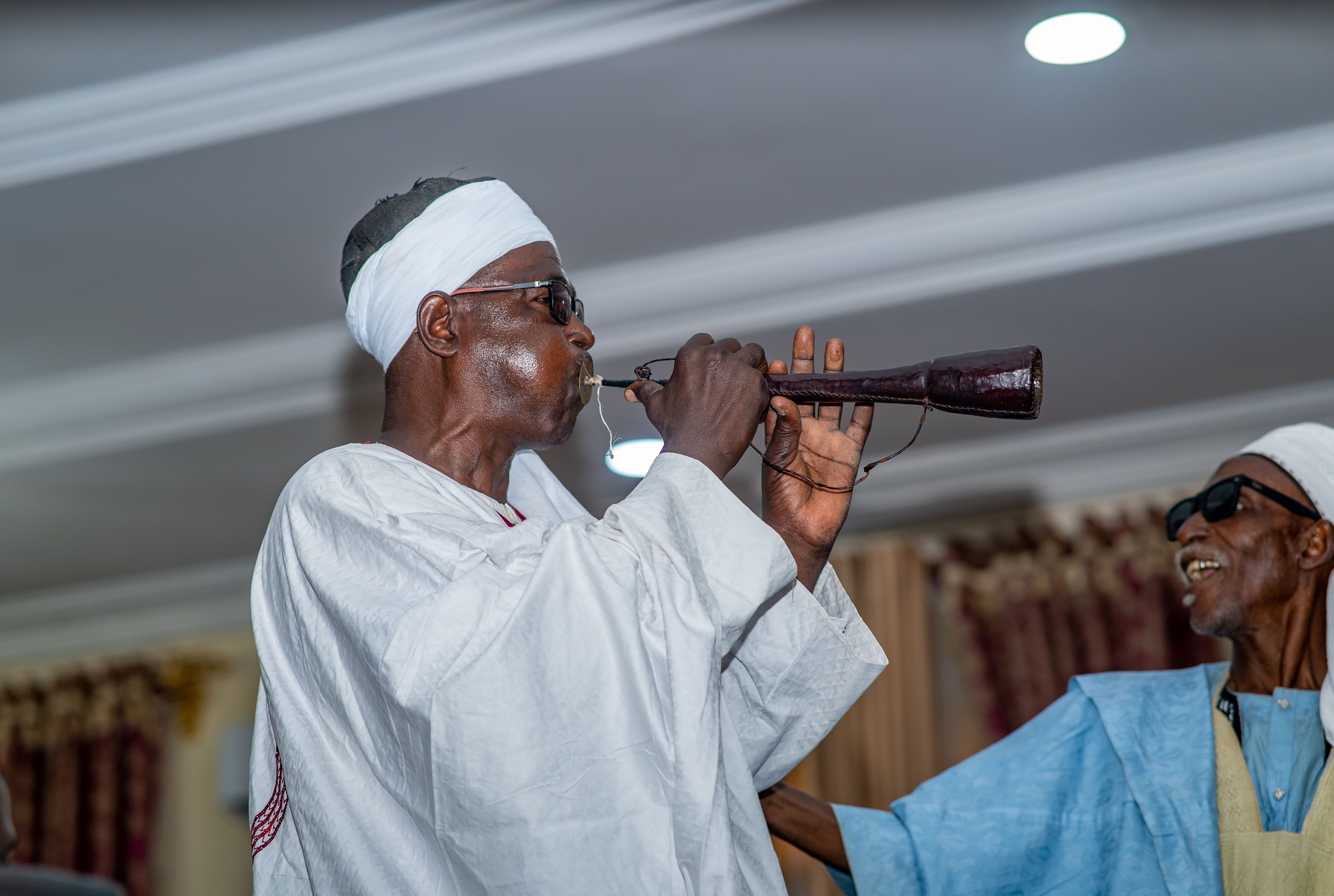 Musician performing with traditional instrument in a cultural setting in Zaria, Nigeria.