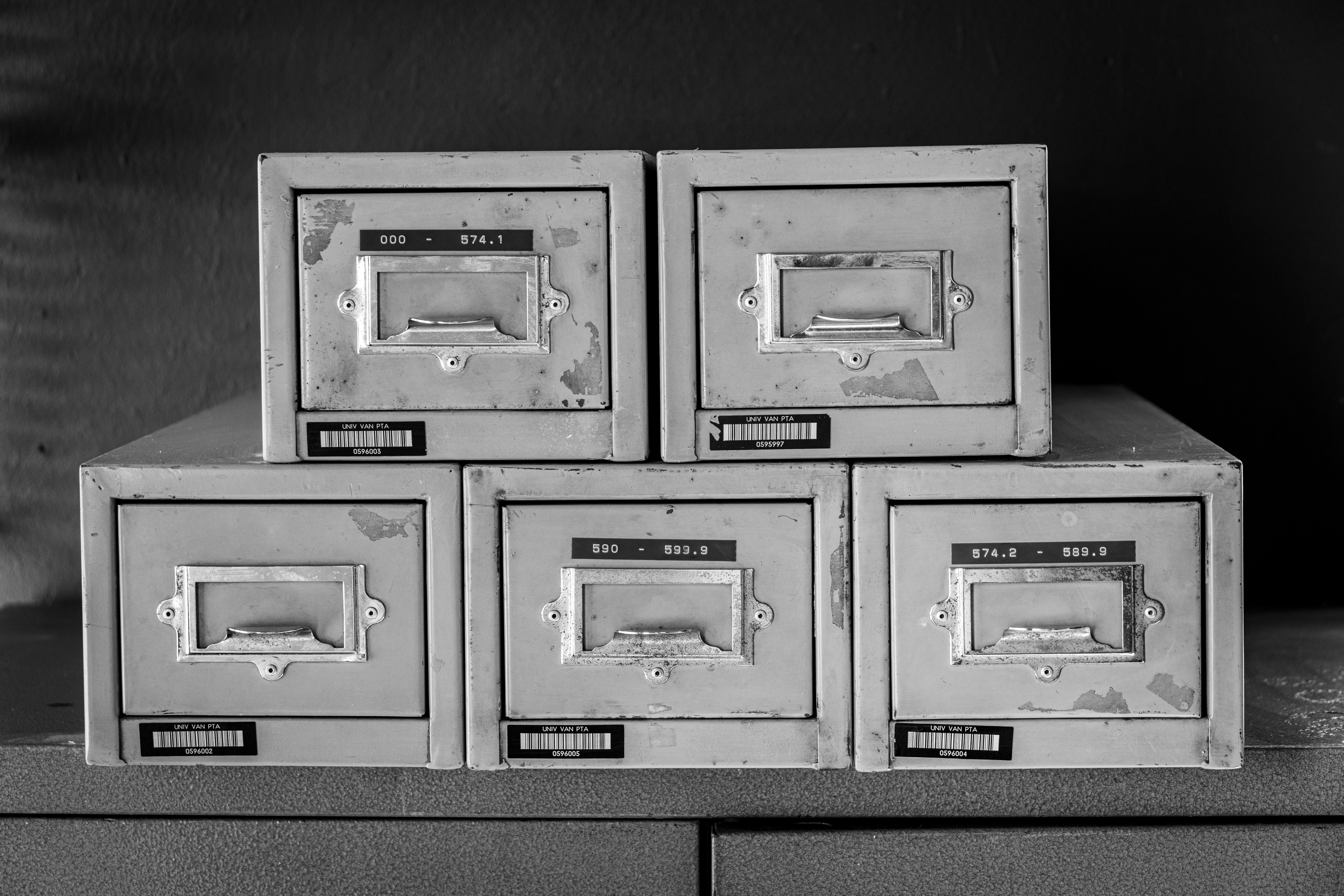 A set of five vintage metal file cabinets, aged and worn, displayed in black and white.