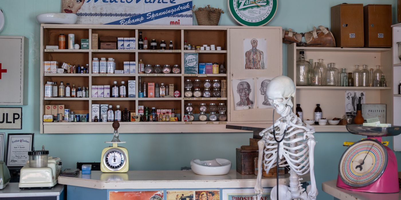 A nostalgic view inside an old-timey pharmacy featuring vintage medicine bottles and a medical skeleton on display.