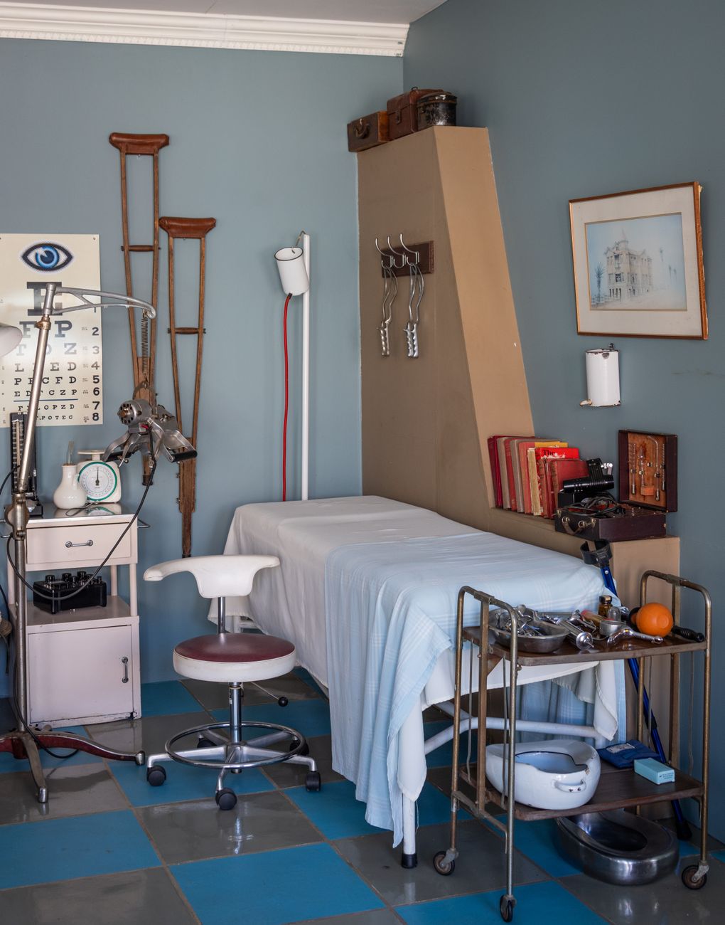 Een retro medische kantooropstelling met een onderzoekstafel, instrumenten en vintage decor.