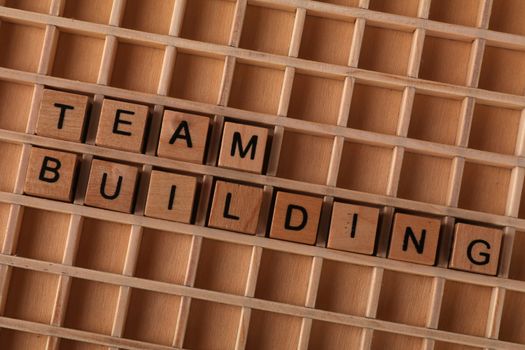 Wooden letter tiles spelling 'Team Building' on a grid surface to symbolize collaboration.