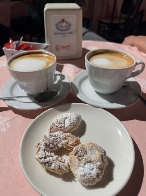 Free Cappuccinos with pastries at a sunlit café table in Lucca, capturing Italian morning charm. Stock Photo