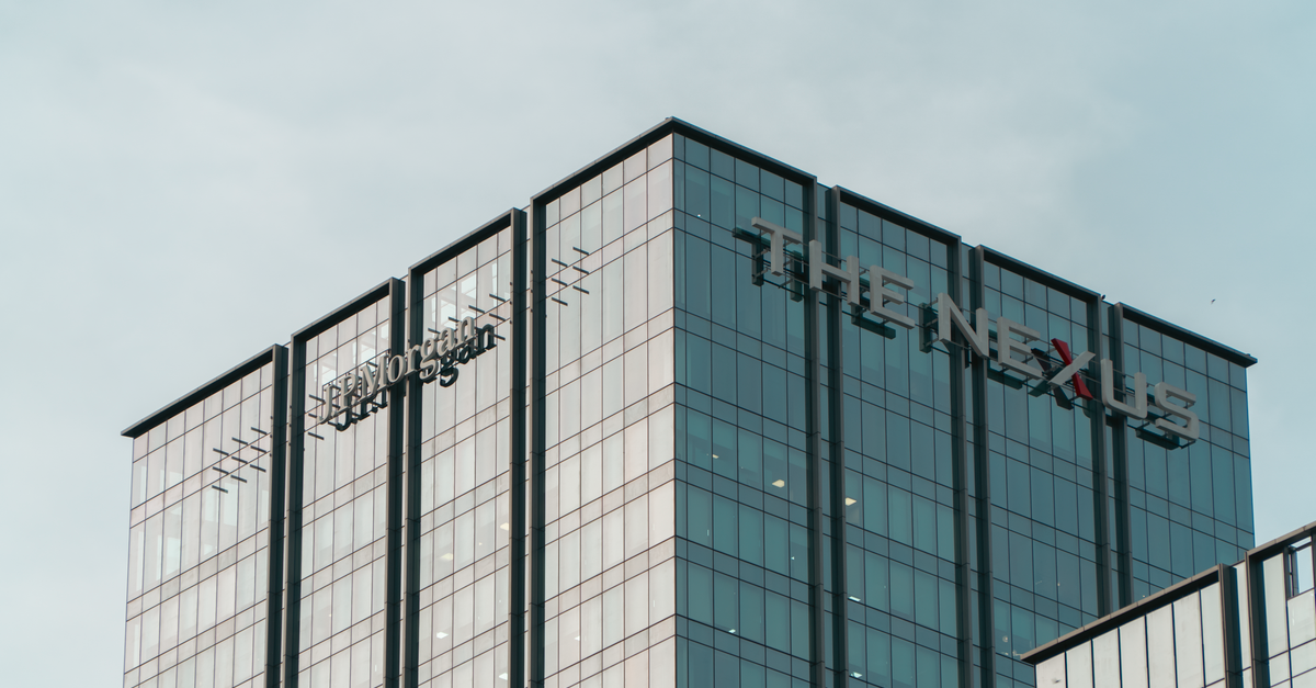 High-rise glass building with 'The Nexus' sign under clear sky.