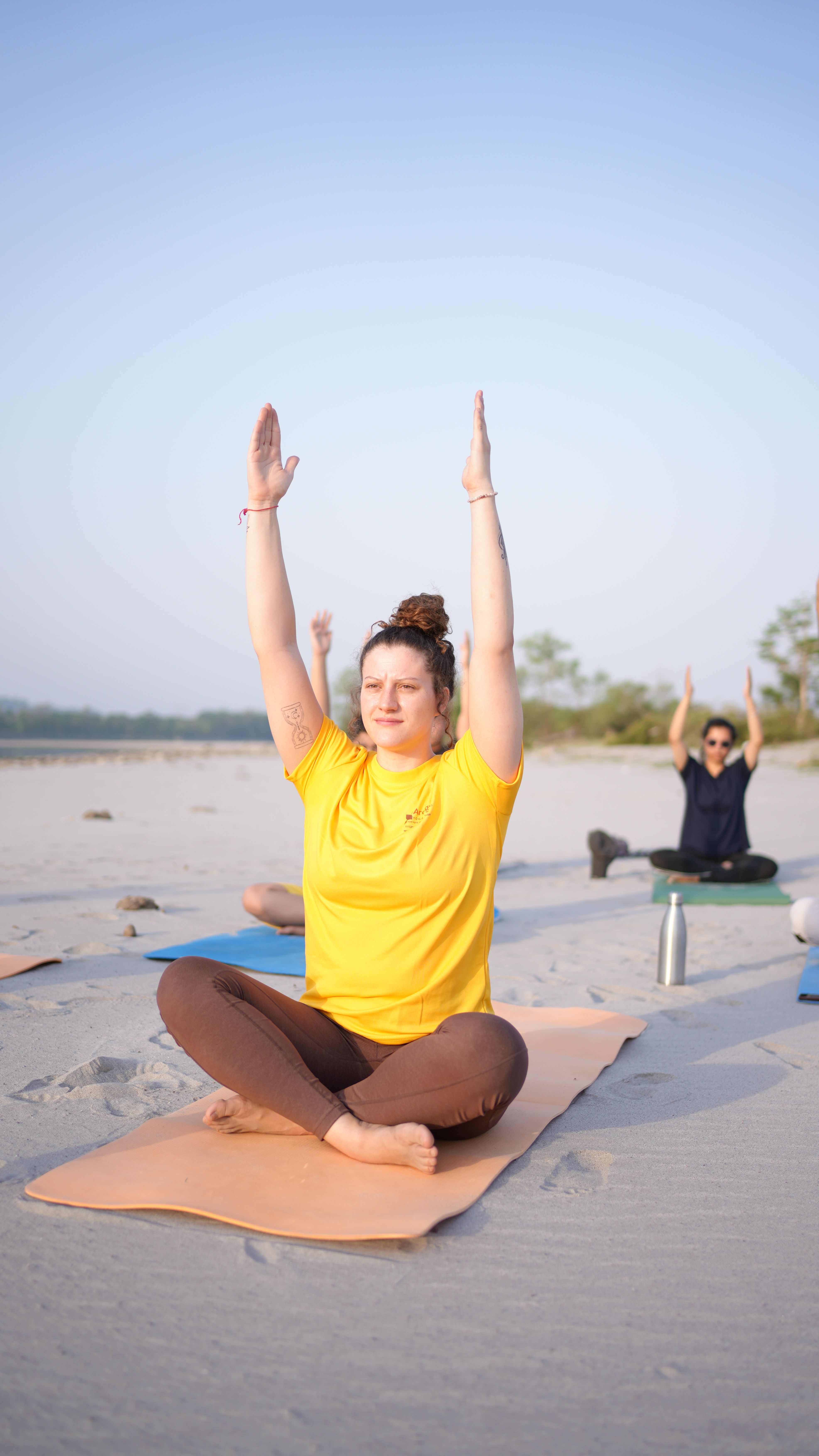 Participants in a serene yoga class on a sandy beach, practicing morning asanas.