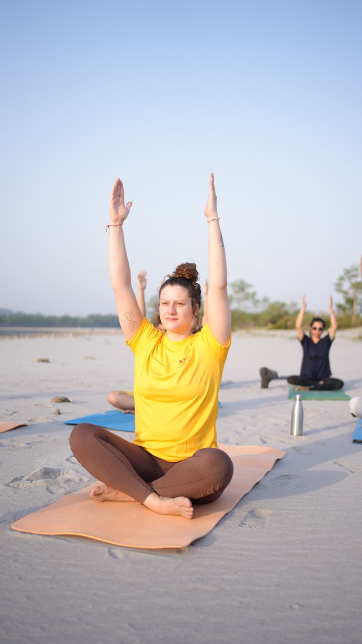 Participants in a serene yoga class on a sandy beach, practicing morning asanas.