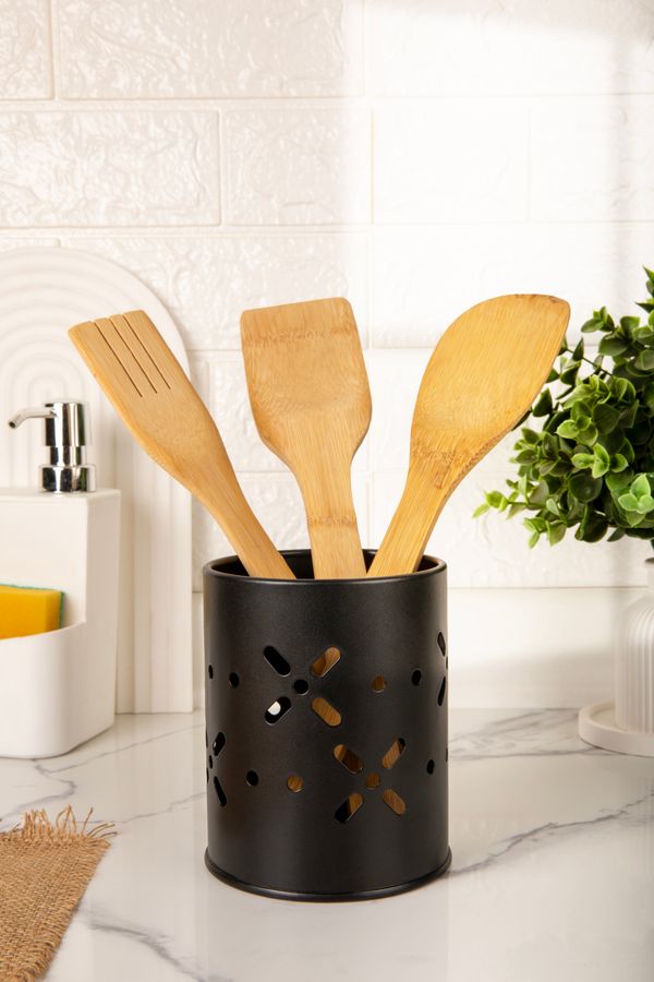 Bamboo kitchen utensils stored upright in a black holder on a small kitchen counter