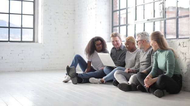 A diverse group of colleagues collaborating on a laptop in a bright modern office setting.