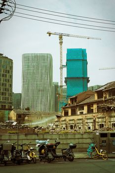 Contrasting architecture of modern skyscrapers and older residential area under construction in Shanghai's urban landscape.