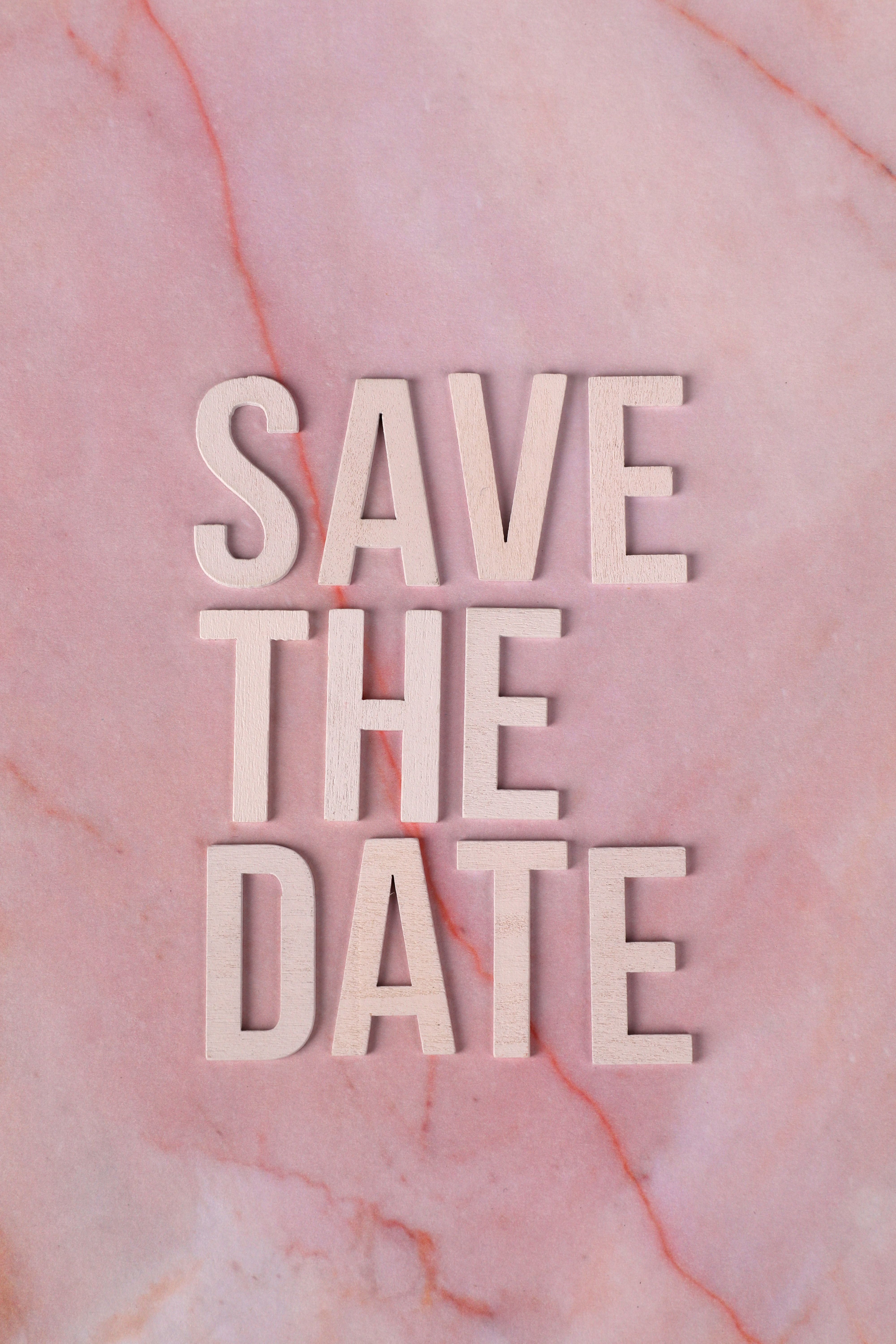 Stylish 'Save the Date' text on a pink marble background. Perfect for wedding invitations.