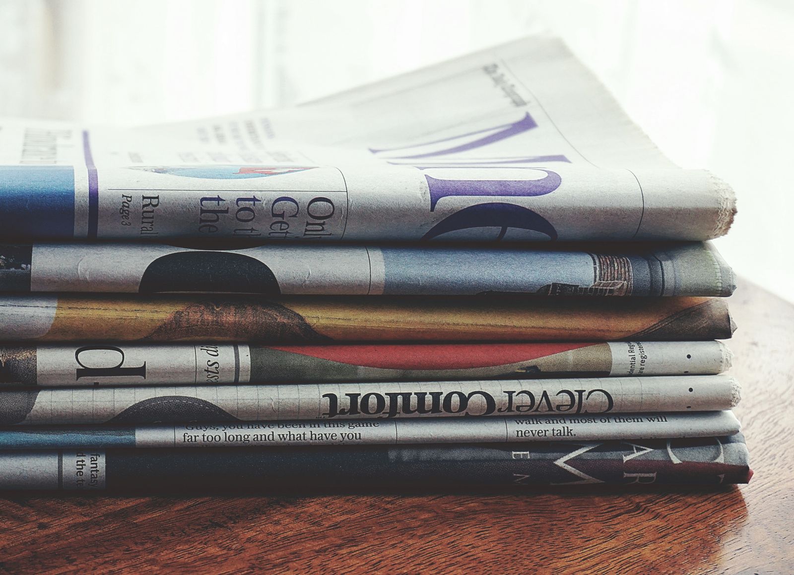 A stack of folded newspapers on a wooden table