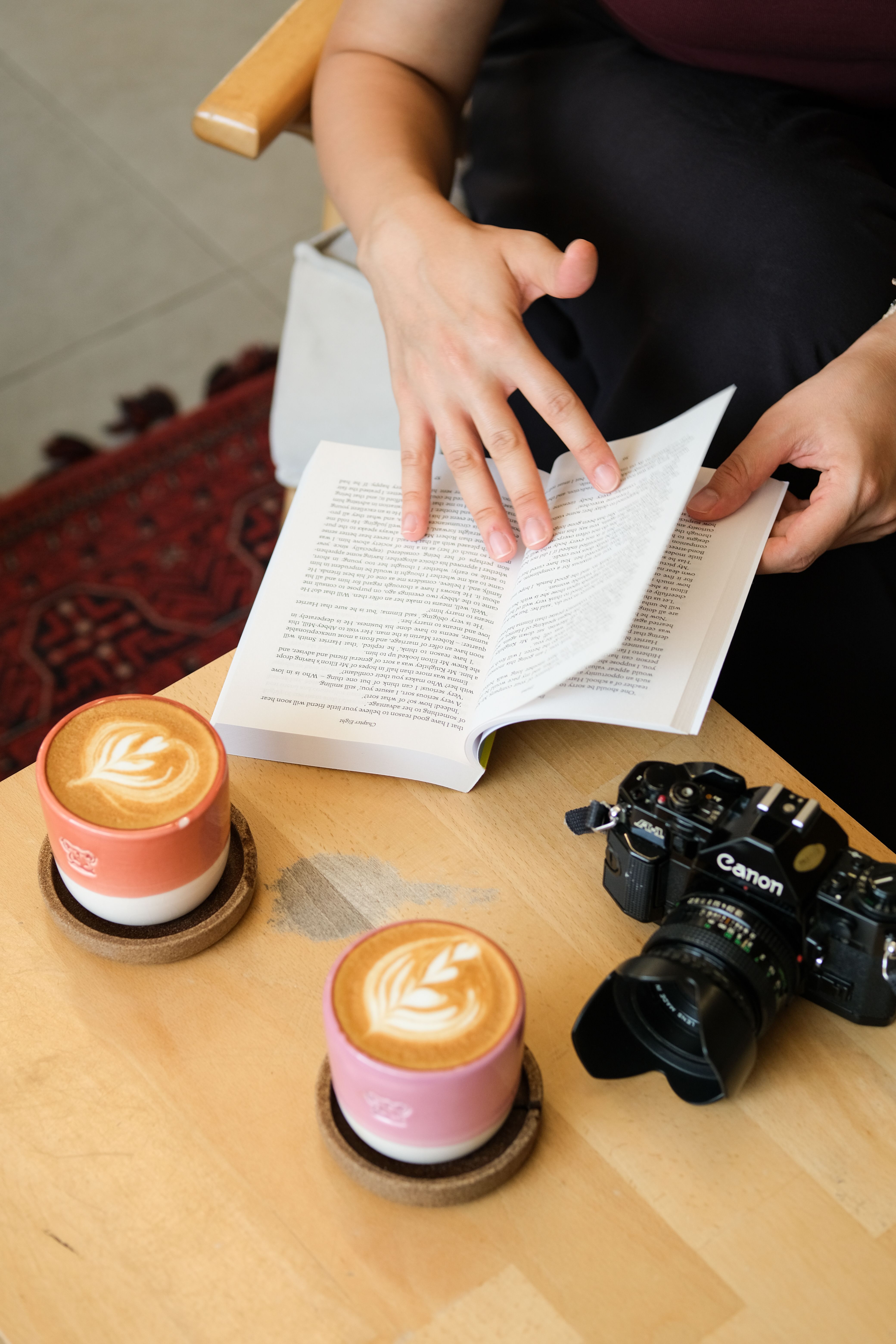 A cozy setting featuring latte art, a book, and a camera—perfect for coffee lovers.
