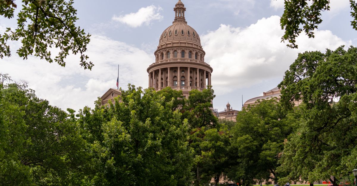 View of the Texas State Capitol dome amidst lush greenery on a sunny day in Austin.