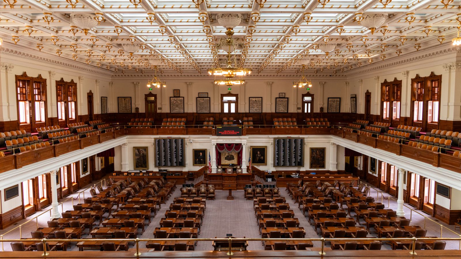 Spacious interior of the Texas State Capitol House Chamber with seating and elaborate ceiling.