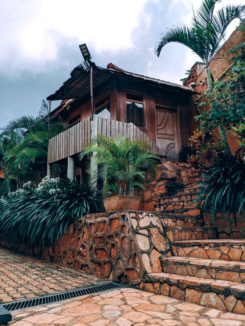 Free Charming wooden house surrounded by lush tropical plants and stone steps. Stock Photo