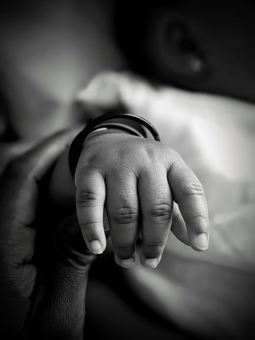 Free Close-up of a baby's hand held gently by an adult, captured in black and white. Stock Photo