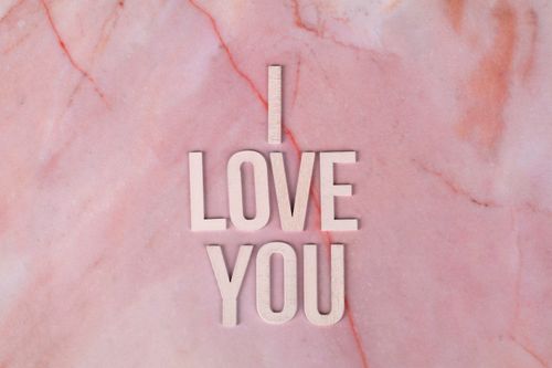 Free Wooden letters spelling 'I Love You' on a pink marble surface. Perfect for romantic and love themes. Stock Photo