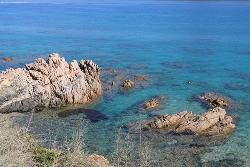 Free A serene coastal scene featuring rocky formations in clear blue waters under a bright sky. Stock Photo