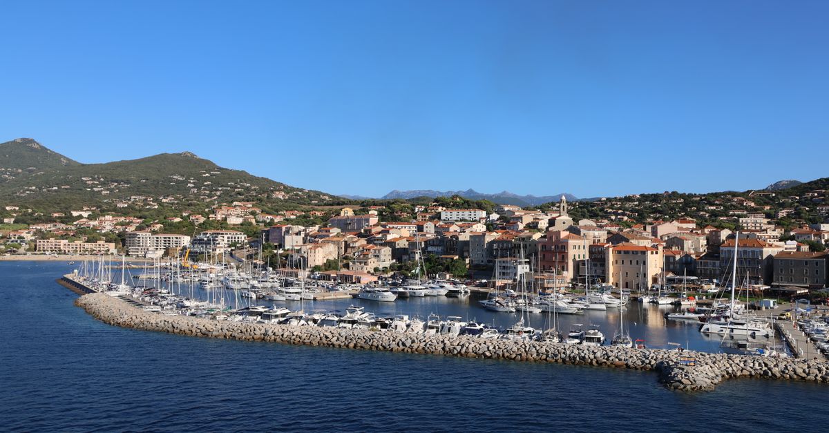 Magnifique vue aérienne de la marina de Calvi en Corse mettant en valeur des yachts et un paysage pittoresque.