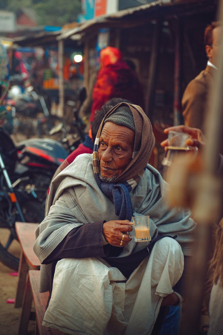 An Elderly Man Sitting While Holding A Cup Of Coffee