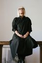 一位白发资深女性身着别致黑色礼服坐在室内，气质优雅
