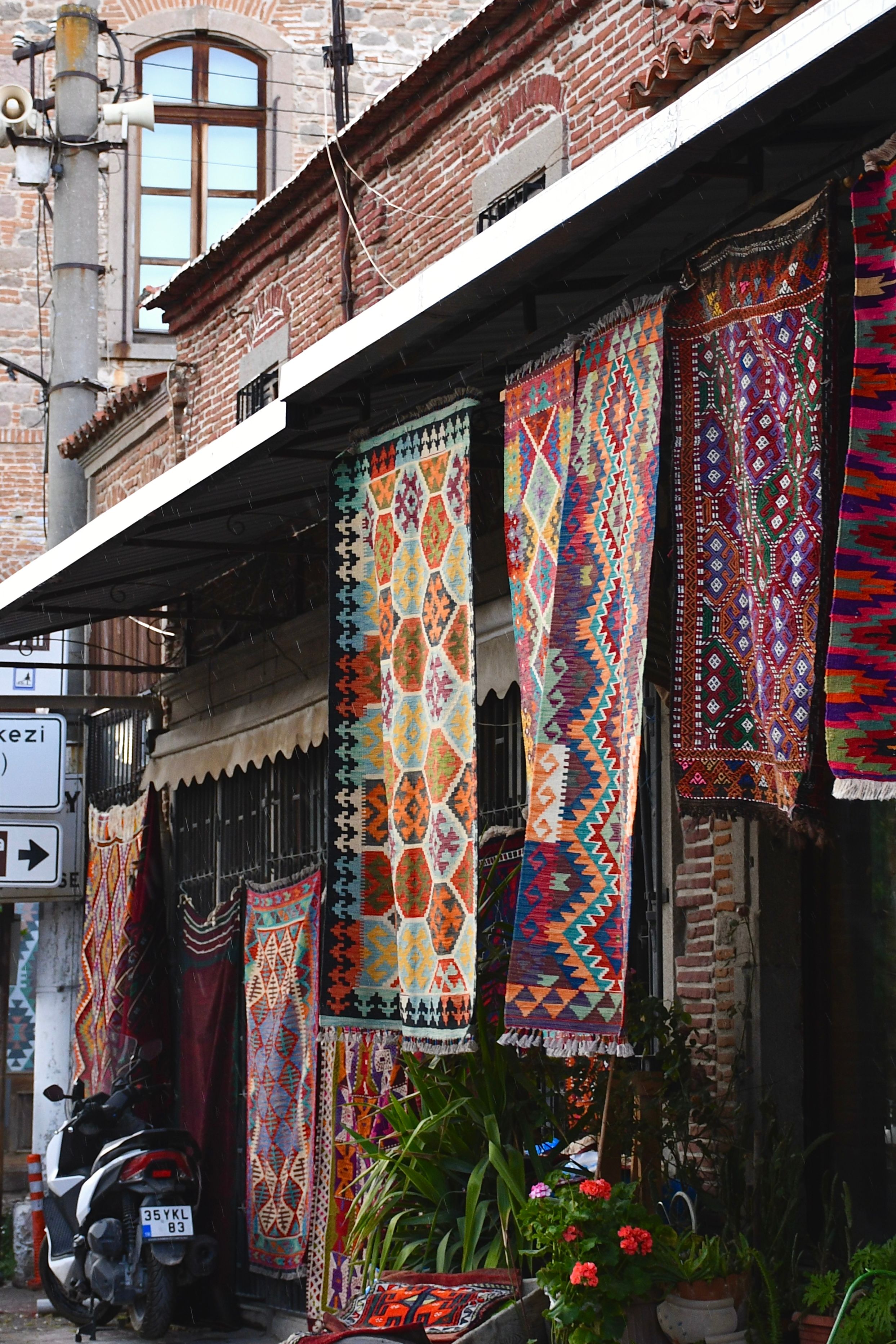 Vibrant display of traditional Turkish rugs in an outdoor street market setting.