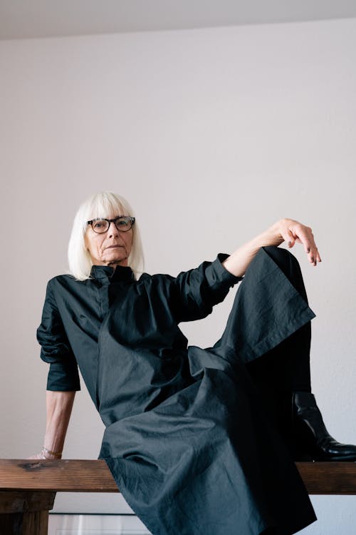 Woman in Black Long Sleeve Dress Wearing Black Framed Eyeglasses Sitting on Table