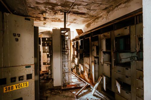 Free An eerie abandoned control room with damaged electrical panels and debris. Stock Photo