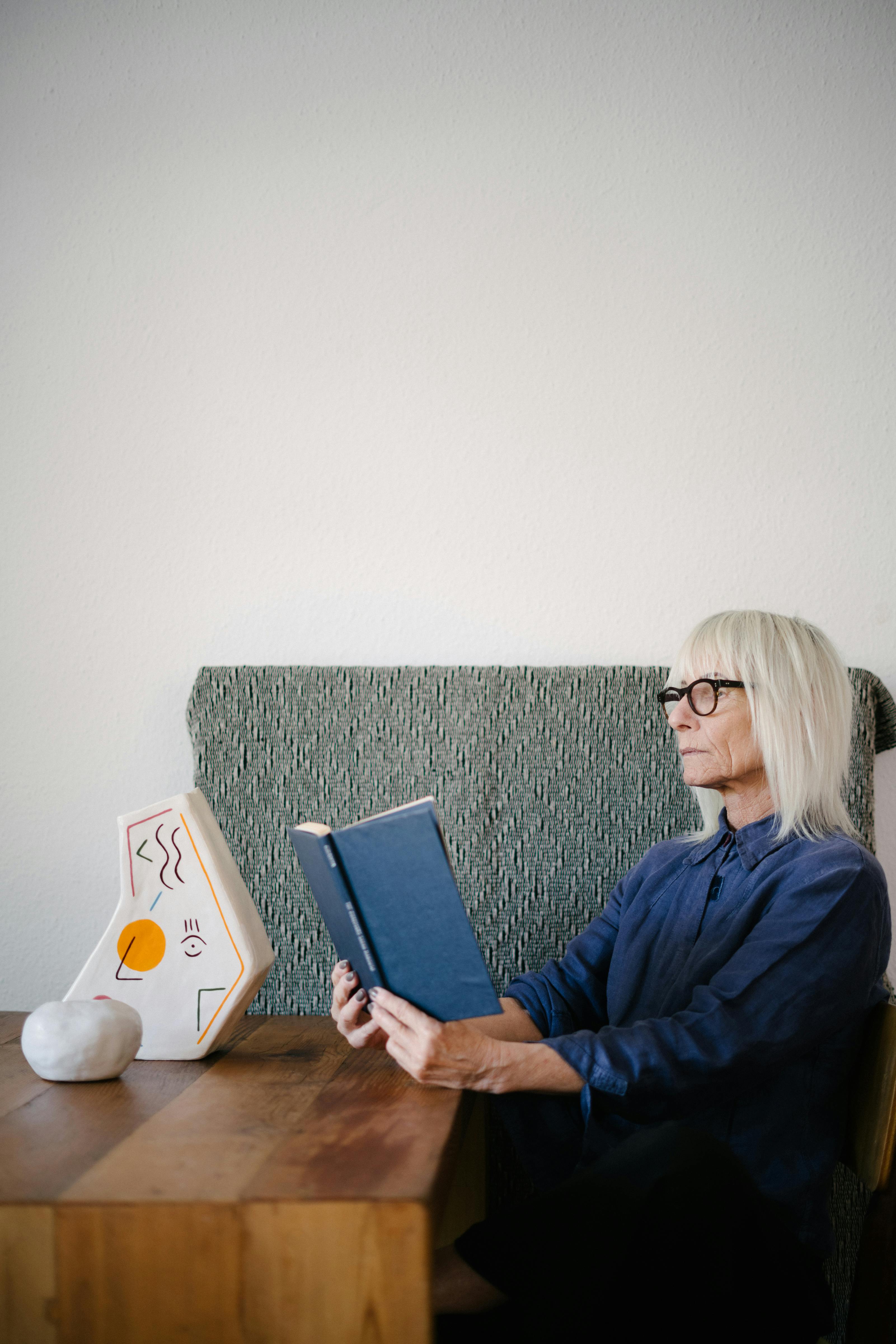 serious senior woman reading book in living room