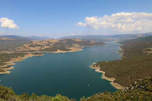 Free Stunning aerial view of a clear blue lake surrounded by mountains under a bright sunny sky, perfect for travel imagery. Stock Photo
