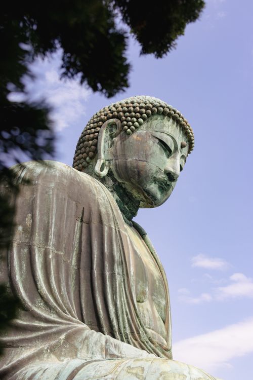 Free A serene side view of the Great Buddha statue in Kamakura against a clear blue sky. Stock Photo