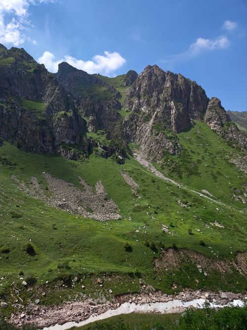 Free Stunning landscape of rugged mountain peaks and lush green slopes under blue sky in Almaty, Kazakhstan. Stock Photo