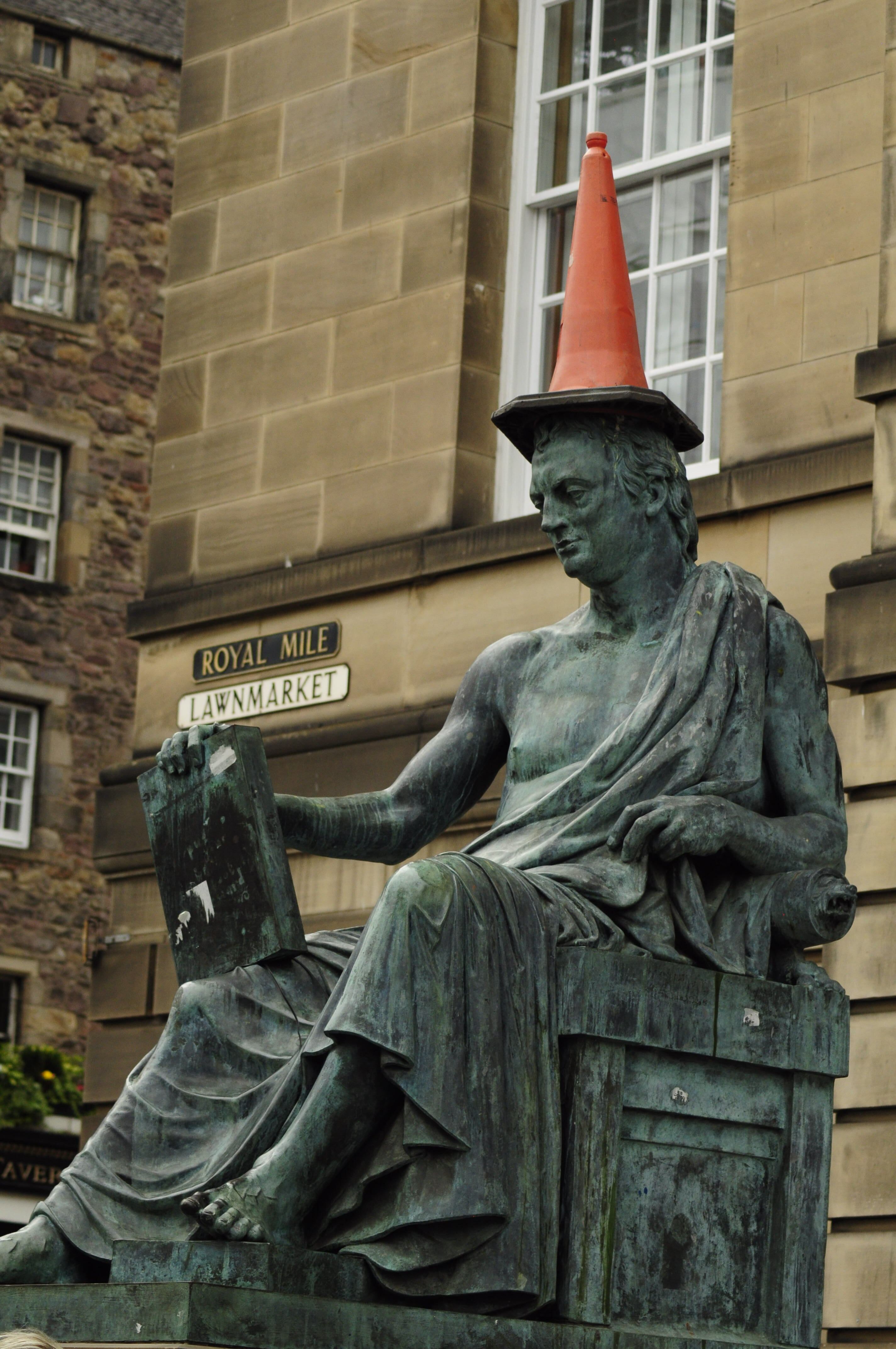 Humorous image of a bronze statue on Edinburgh's Royal Mile with a traffic cone hat.