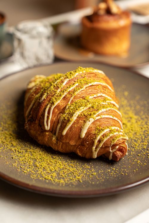 Free Indulge in a gourmet croissant with pistachio topping for a perfect fine dining experience. Stock Photo