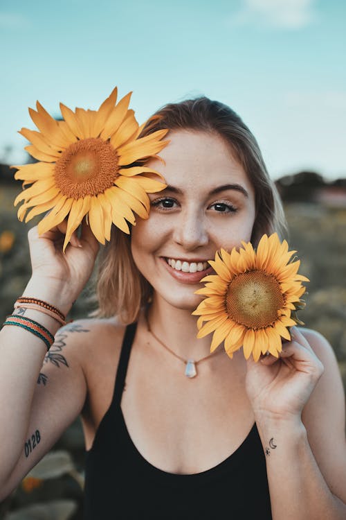 Woman in Black Tank Top Holding Sunflowers Smiling